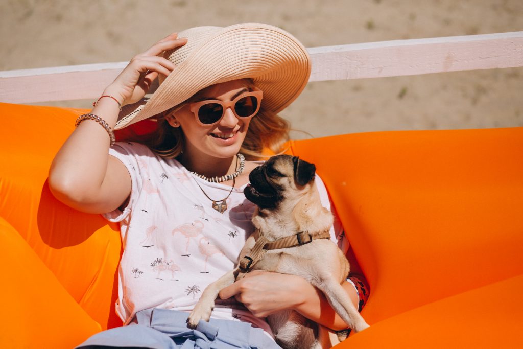 A imagem mostra uma mulher curtindo o sol, no verão, com seu pet.